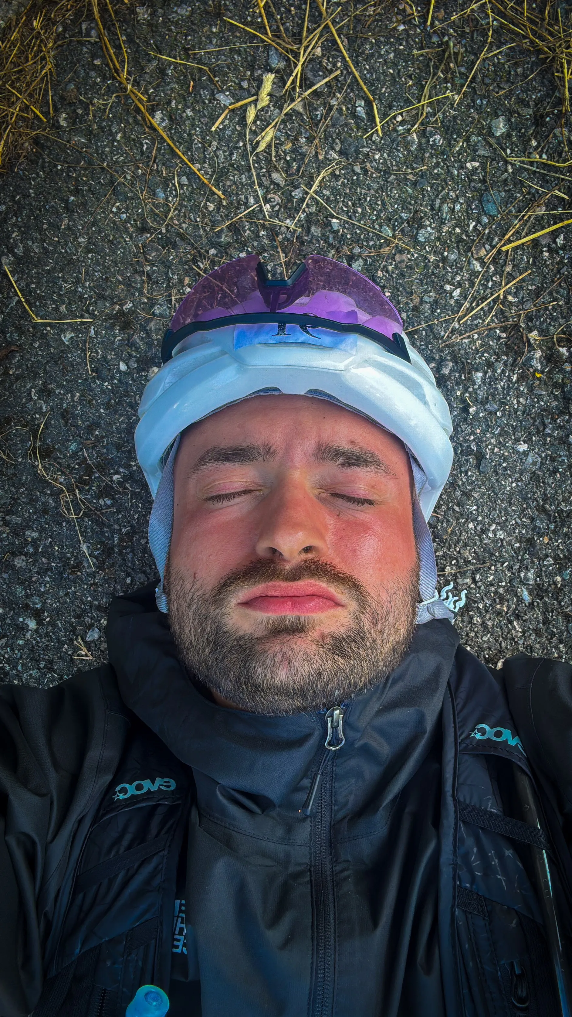 Sabin Mujagic erschöpft auf dem Asphalt liegend, mit Helm und Radjacke, beim Race Across Germany